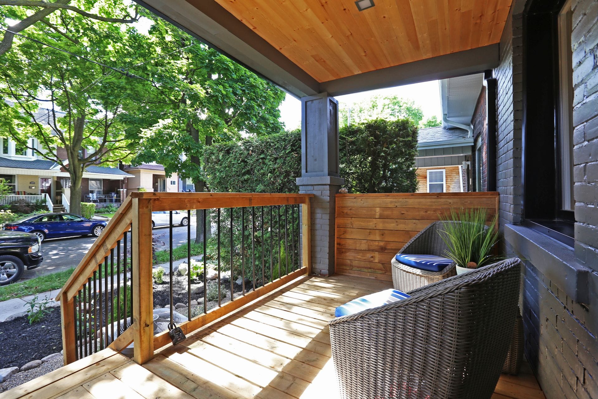 Cozy wooden porch with chairs and greenery.