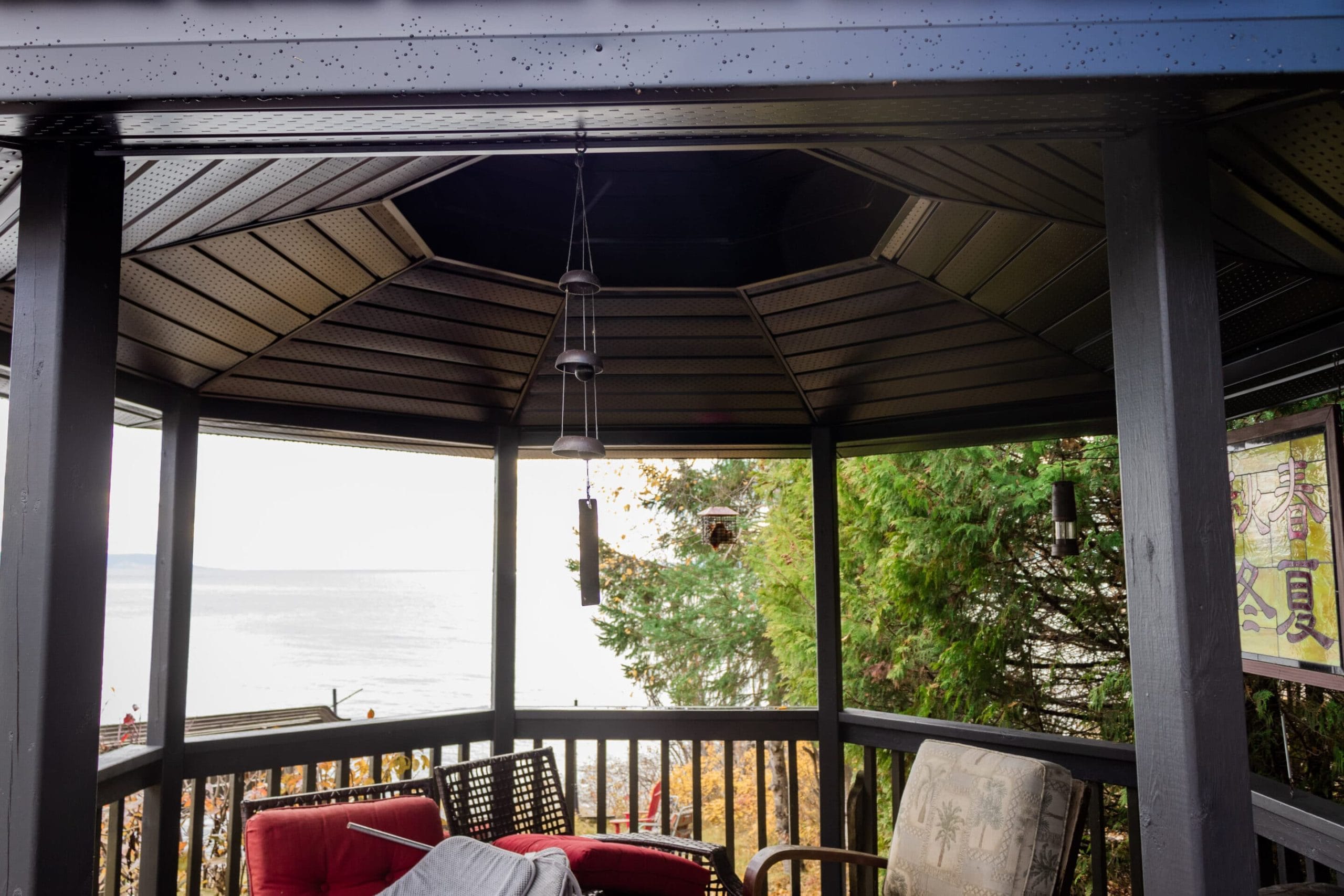 Cozy gazebo with lake view and red chairs. Outdoor Living by True North General Contractors