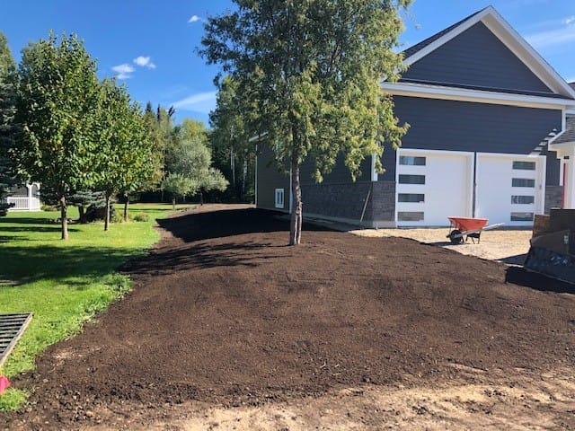 Freshly landscaped yard with new soil near house.